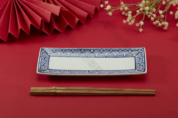 中国风格的红色背景和红色折扇，小花，吉祥的云型长盘和竹形筷子