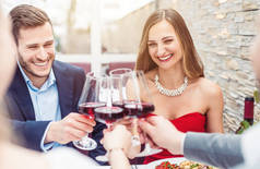 人们坐在餐桌上用红葡萄酒祝酒
