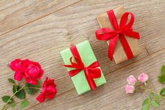 木制木板上有美丽玫瑰的礼品盒。假日送礼的概念.顶部视图.