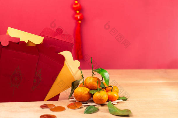 中国农历新年的装饰。中国信封，橙色，叶子，红包，木制红色背景。（关于信封的文字意味着新年快乐和幸福)