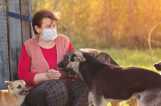 戴着医疗面罩的女志愿者和无家可归的狗站在户外。志愿服务和动物收容所的概念。<strong>当你</strong>有狗的时候会更孤独