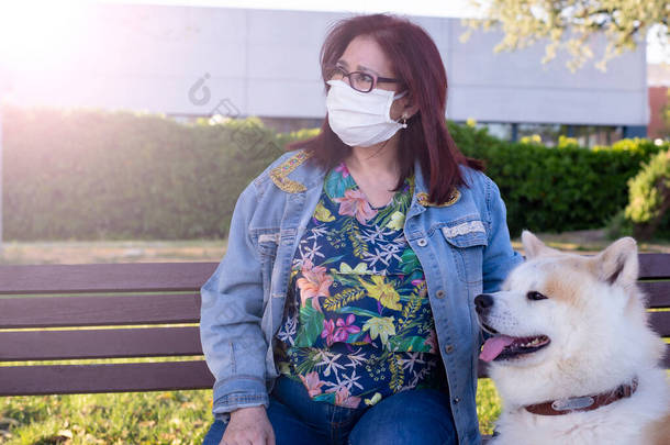 一名妇女带着她的狗和医疗面具坐在公园的<strong>面包车</strong>里，受到检疫