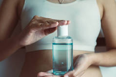 女用手拿着清洁剂凝胶瓶，用于家庭中的手卫生验尸保护