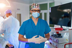 戴面具、擦拭、眼镜和乳胶手套的医生。背景下,外科医生在明亮的现代手术室进行外科手术.手术室。诊所的现代设备。急救室.