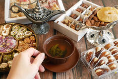 东方糖果，坚果，糖果，金属花瓶，茶，木制背景的枣子，特写