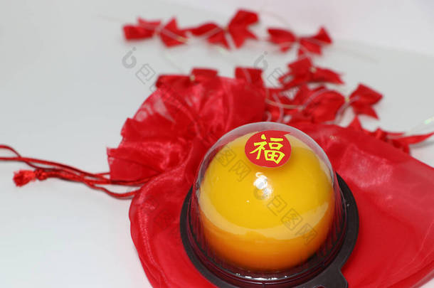 中文：幸福，粘在<strong>红色布</strong>袋上的橙子蛋糕上，把红丝带放在白色地板上。农历新年概念.