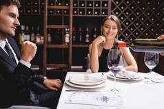 酒水倒入玻璃杯的选择焦点- -就近坐在餐厅餐桌旁的典雅夫妻 