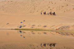 巴丹湖反映了一个小型旅游团乘坐巴克特里安骆驼穿越戈壁沙漠的巴丹贾兰-巴丹尼林沙莫湖-神秘湖泊沙漠。阿尔萨高原-内蒙古-中国