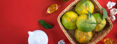 在中国农历新年水果的概念中，新鲜成熟的橘子和鲜叶放在红色桌子的背景上，中文意思是春天.