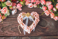 粉色编织的老式心脏在深色木制背景与粉红色的花。情人节的概念.
