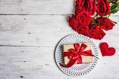 浪漫的餐桌。情人节或母亲节的爱的概念，结婚餐具。一束新鲜的勃艮第玫瑰，喜庆的礼物，旧木桌
