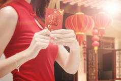 穿着旗袍的中国女人拿着红包。新年快乐