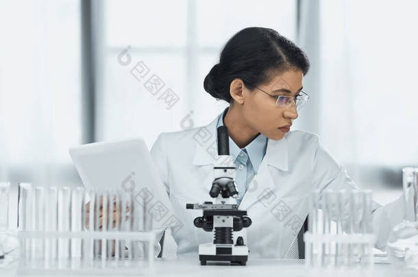 戴眼镜、在显微镜附近拿着<strong>数码</strong>平板电脑、在实验室拿着试管的非洲裔美国科学<strong>家</strong> 