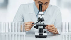 非洲裔美国科学家在实验室试管附近通过显微镜观察 