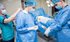 手术前助手帮助外科医生戴上乳胶手套和手术礼服.