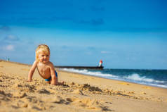 快乐的小男孩在海边的沙滩上爬行