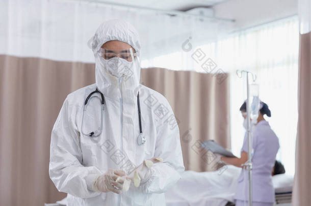 身穿COVID防护服的医生正在摘取手套。医生们戴着COVID-19防护手套，在国家检疫控制区对病人进行检查和治疗.