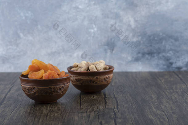 一碗碗健康的干<strong>杏仁</strong>水果和花生放在木制桌子上的壳里。高质量的照片