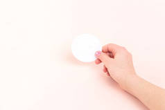 女孩手里拿着圆圆的空白贴纸，贴在彩色粉红的桃色背景上。做动机题词或你自己的贴纸设计