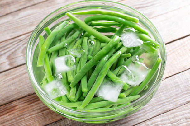 煮沸的蔬菜，在木桌上漂白后放入冰水中的绿豆