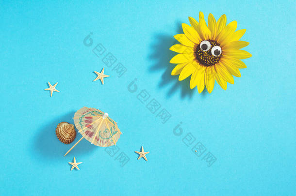 太阳是由有眼睛、阳伞、贝壳和海星的葵花子制成，躺在淡<strong>蓝色</strong>的背景上。简<strong>约创意</strong>海滩概念，平铺构图