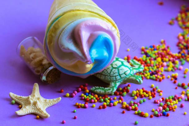 色彩艳丽的雪糕在华夫饼杯里，一只乌龟和一只海星在紫色的背景上平平淡淡的。2021年夏天流行的色彩- -淡蓝色、粉色、黄色。高热量美味的甜食。夏季食品概念