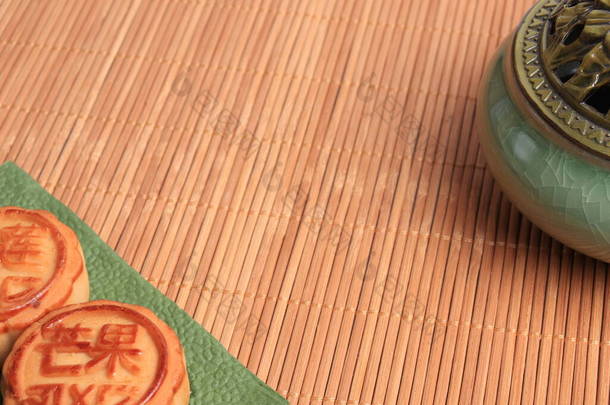 中国月饼和香炉在竹子<strong>背景</strong>上.亚洲传统的<strong>中秋节</strong>。象形文字的翻译：芒果、石榴和荷花.