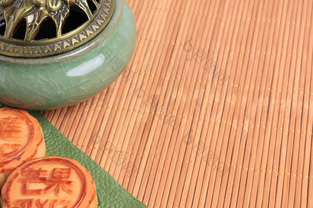 中国月饼和香炉在竹子背景上.亚洲传统的中秋节。象形文字的翻译：芒果、石榴和荷花.