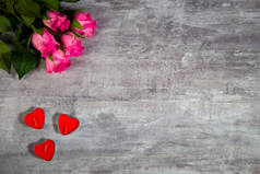 粉色玫瑰和红蜡烛的密闭镜头，心形，躺在灰色的木制表面