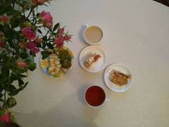 Breakfast for two with tea and cakes with roses in a vase