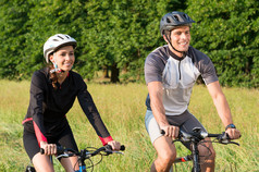 年轻夫妇骑自行车在草地上