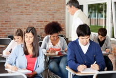 学生的写作考试时老师监督他们在教室里了。