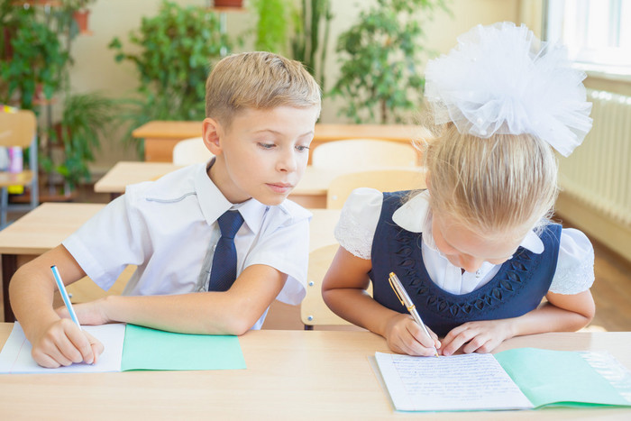 学生或同学在学校教室里一起坐在桌前