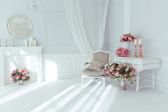 豪华干净明亮的白色内饰。宽敞的房间配阳光和鲜花的花瓶,