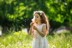 小女孩在草地上吹白色蒲公英. 