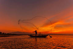 在日出的时候，缅甸抛网捕鱼茵莱湖的传统渔民的剪影