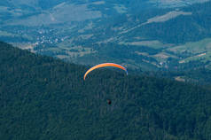 在阳光明媚的夏日，滑翔伞飞过一个山谷. 