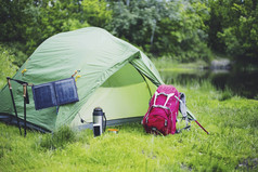 在河岸上露营。太阳能电池板悬挂在帐篷上.