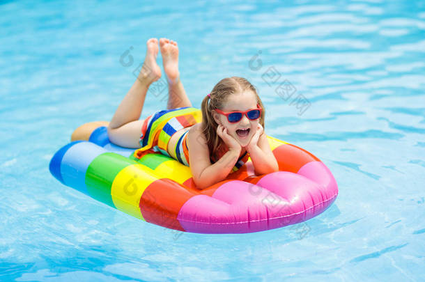 快乐的孩子在充气冰淇淋漂浮在热带度假胜地的户外游泳池。和孩子们一起度过暑假。为儿童提供游泳和穿衣。水玩具。漂浮在五颜六色的木筏的小女孩.