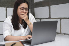 疲惫的昏昏欲睡的商业妇女在眼镜打呵欠, 而使用笔记本电脑在办公桌工作到深夜。无聊的学生在晚上的电脑阅读演示准备考试。过度劳累, 教育