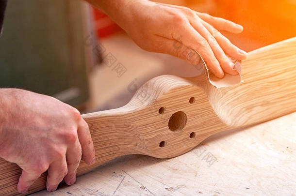 有经验的木匠在工作衣物和小付多少营业税所有者在木工车间工作, 用砂纸抛光木在车间工作台  
