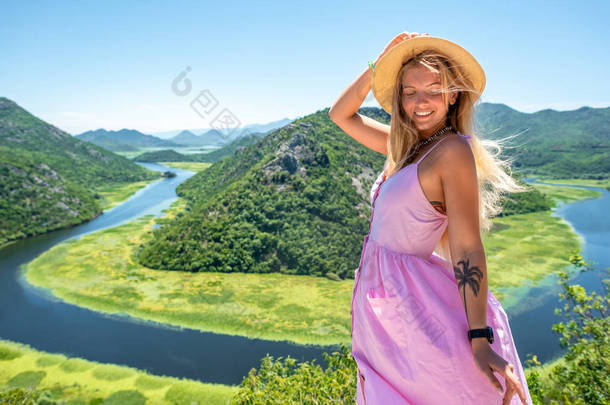 在黑山 Crnojevica 河 (里耶卡 Crnojevica) 附近的粉<strong>红色礼服</strong>和帽子微笑的妇女