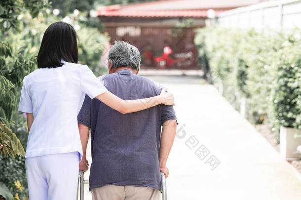 护士与病人使用沃克在退休回家。年轻的女护士抱着老人的肩膀在户外花园散步。高级护理、护理人员和高级退休<strong>家庭服务</strong>概念.