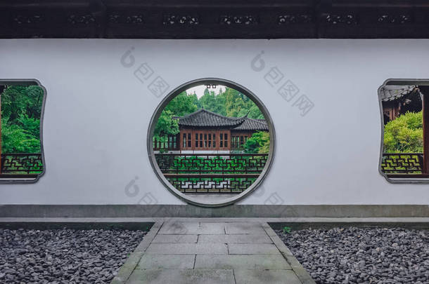 在中国杭州西湖附近的中国花园中, 通往赏见中国传统建筑的月亮门的道路