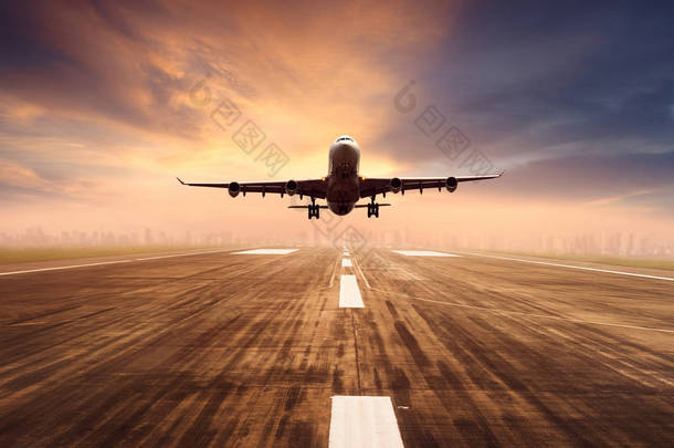 航空飞机飞越<strong>机场</strong>跑道与城市景观和日落天空背景