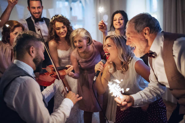 一位年轻的新娘、新郎和其他客人在婚宴上跳舞唱歌.