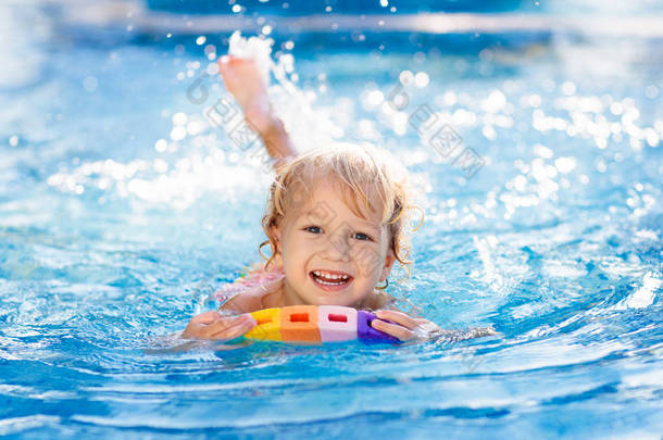 孩子们在热带旅游胜地的室外游泳池里学习游泳。孩子们学习游泳。幼儿的锻炼和培训。小男孩在体育<strong>俱乐部</strong>有五彩缤纷的浮板.游泳的婴儿或幼儿.
