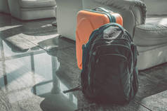 一个黑色的背包和一个橙色的手提箱站在接待大厅。旅行行李