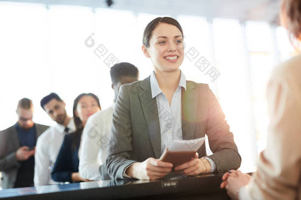 成功的年轻商务专业人士在柜台值机经理微笑，同时咨询航班详情
