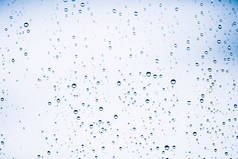 脏窗户玻璃与雨滴。大气蓝光背景与雨滴。水滴和污渍特写。宏中具有复制空间的详细透明纹理。雨天.